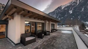A modern building with a flat roof, large glass windows, and outdoor seating.