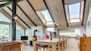 Une pièce spacieuse avec un plafond en bois, une table à manger avec des chaises, un canapé et un téléviseur.