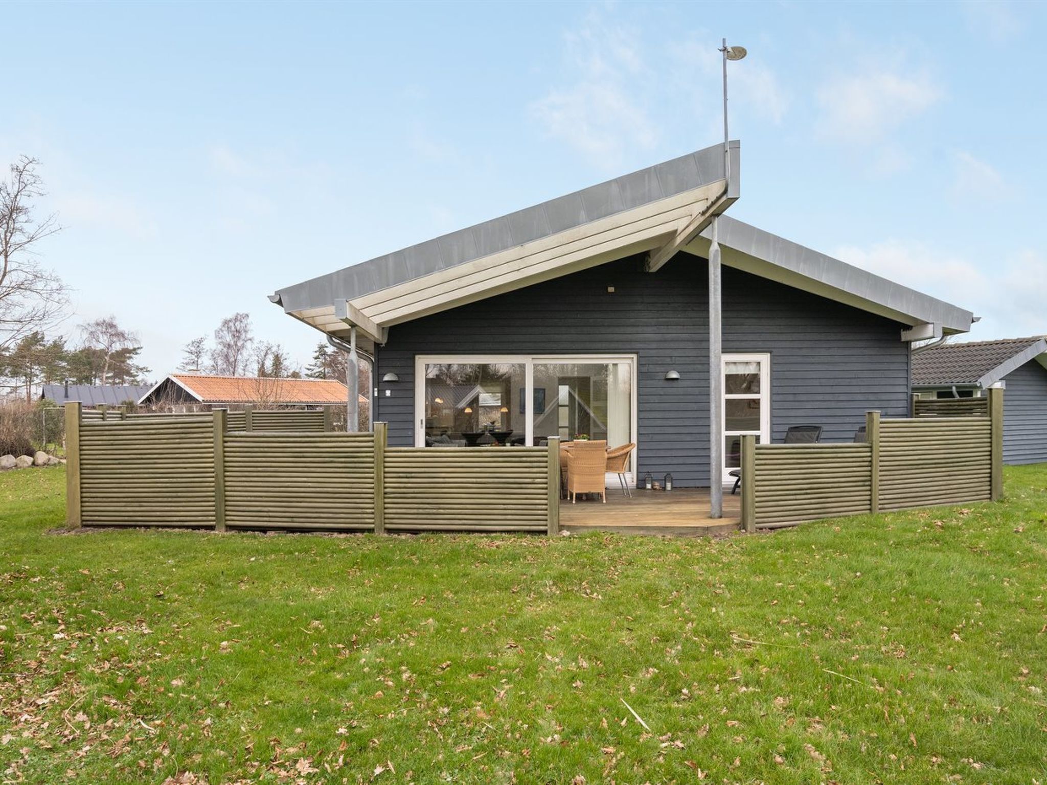 A modern house with a sloped roof, a covered patio, and a fenced yard.