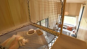 A room with a netted window, a bed with a plaid blanket, a teddy bear, and a chessboard.