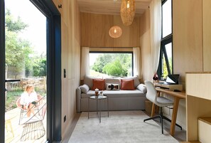 A modern interior with a sofa, a small table, a desk, and a large window.