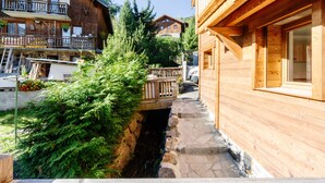 Un edificio de madera con un camino de piedra, un puente de madera y un pequeño arroyo.