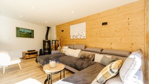 Una sala moderna con un sofá modular, una mesita redonda y una pared de madera.