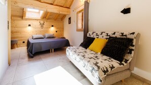 Una habitación con una cama, un sofá, una mesita y una lámpara en la pared.