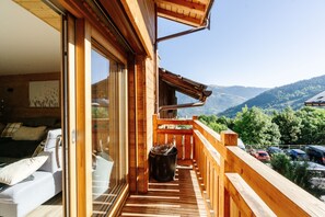 A wooden balcony with a view of mountains, a sofa, and a trash bin. - Chalet "Meribel d'Eugénie" with Wi-Fi (Les Allues)