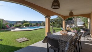 Eine Terrasse mit Tisch und Stühlen, ein Pool und eine Aussicht auf die Landschaft.