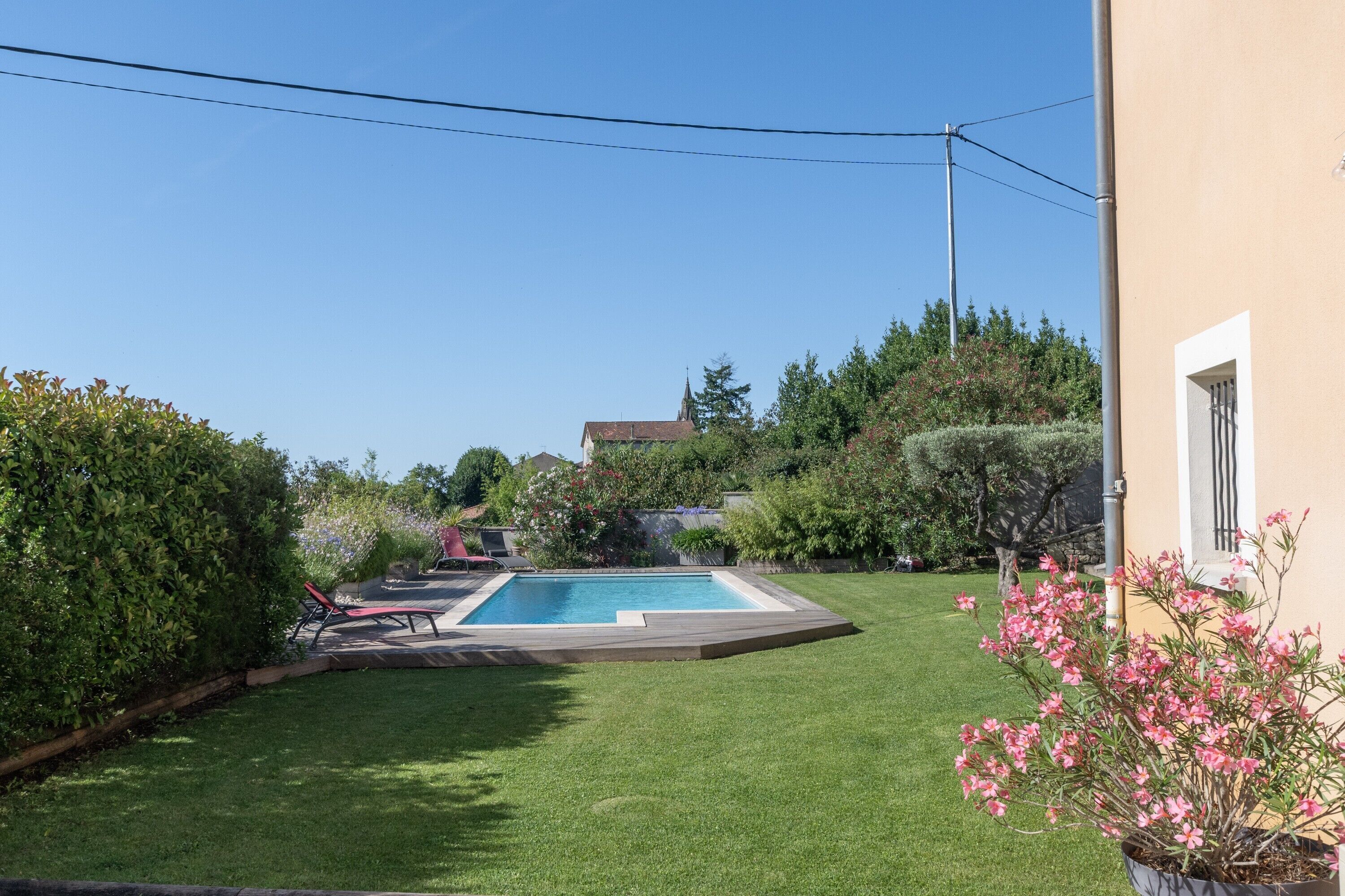 Un patio trasero con piscina, césped y una casa.