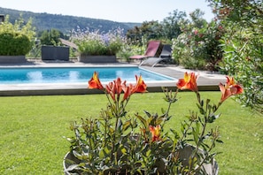 Una piscina con vistas despejadas del jardín circundante y una silla junto a la piscina.