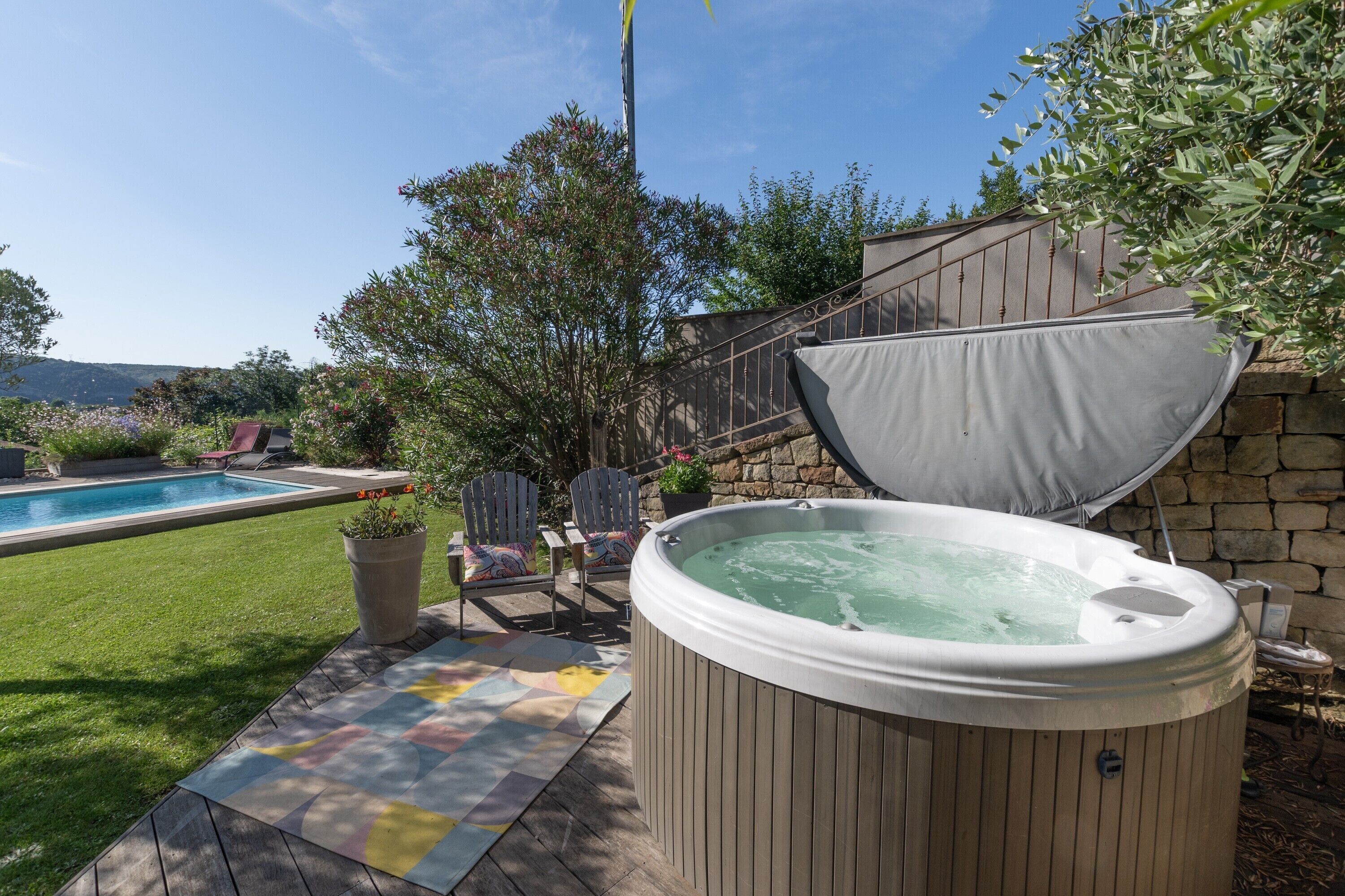 A hot tub, outdoor seating, and a swimming pool in a backyard setting.