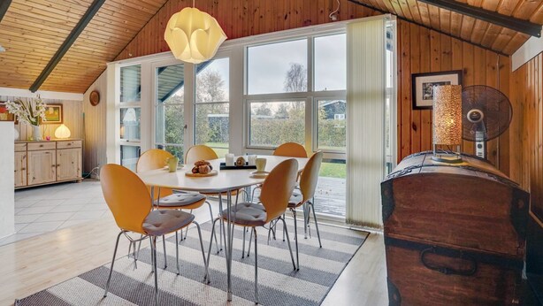 A dining area with a round table, six chairs, and a large window with curtains. - "Simonia" - 600m from the sea by Interhome (Sydals)