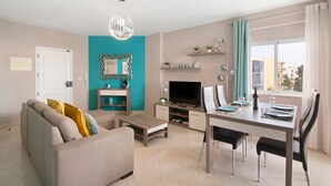 Ein modernes Wohnzimmer mit einer Couch, einem Fernseher, einem Esstisch und Stühlen.