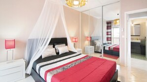 Ein Schlafzimmer mit einem Bett, Nachttischen, einem Spiegel und einer Kandelaber.