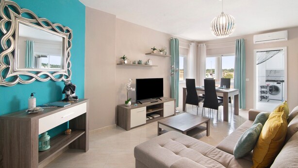 Ein modernes Wohnzimmer mit Fernseher, Sofa und Essbereich.