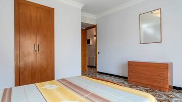 Een slaapkamer met een bed, een kledingkast, een dressoir en een spiegel.