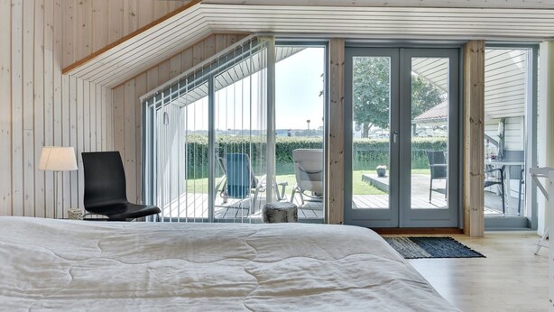 Un dormitorio con una cama grande, una silla y vistas a un patio con mobiliario exterior.