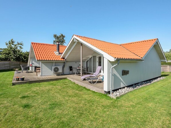 Une maison de plain-pied dotée d’un patio couvert, d’une cheminée et d’une petite terrasse.