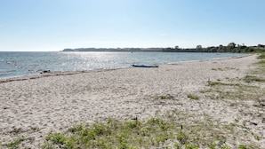 Una playa arenosa con un bote y agua tranquila.