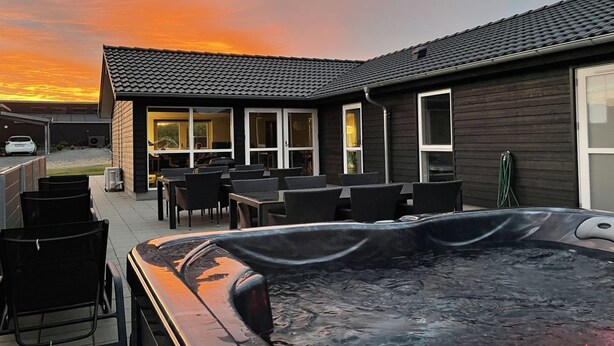 A hot tub in a backyard with a patio area and a building with large windows.