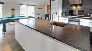 A modern kitchen with a central island, a built-in stove, and a large window.