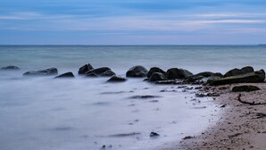 A beach with large rocks and calm water.