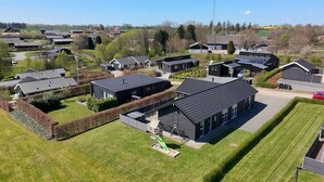 A residential area with modern houses, a playground, and a large building with a dark roof.