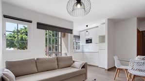 Ein modernes Wohnzimmer mit einer Couch, einem Glastisch und einem Essbereich mit Stühlen.