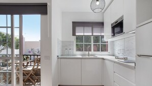 Eine moderne Küche mit weißen Schränken, einem eingebauten Backofen und einem Fenster mit Blick nach draußen.