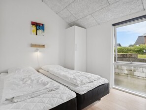 A bedroom with two beds, a large window, and a view of the outside.
