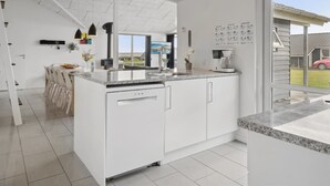 A modern kitchen with white cabinetry, a granite countertop, and a large window offering a view of the outdoors.