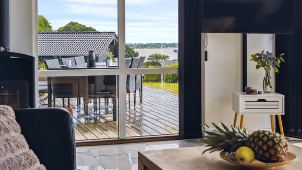 A modern living room with a large sliding glass door leading to an outdoor deck.