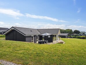 A modern house with a patio area, a covered outdoor seating space, and a grassy yard.