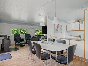 Une cuisine moderne avec des meubles blancs, un coin repas doté d’une table ronde et de chaises, et une vue sur la verdure à l’extérieur.