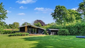 Une maison moderne dotée d’une grande pelouse, d’une terrasse et d’un garage.