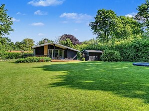 Et moderne hus med en stor græsplæne, en terrasse og en garage.