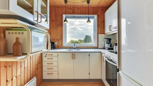 A compact kitchen with wooden cabinets, a built-in oven, and a window providing natural light. - "Ellyn" - 500m from the sea by Interhome (Haderslev)