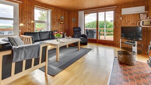 A cozy cabin interior with a wooden ceiling, a sofa, a dining table, and a TV. - "Ellyn" - 500m from the sea by Interhome (Haderslev)