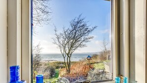 Una ventana con vistas a un árbol, una lámpara y botellas azules en el alféizar.