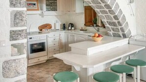 A kitchen with a stone archway, white cabinetry, and a central island with green stools.