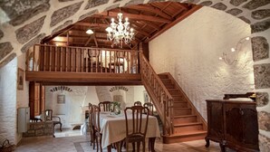 A dining area with a high wooden ceiling, stone walls, and a chandelier.