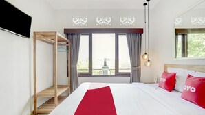 Une chambre d’hôtel avec un grand lit, une étagère en bois, une vue sur l’extérieur et un téléviseur fixé au mur.