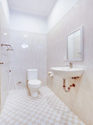 A bathroom with a toilet, sink, mirror, and checkered floor tiles. - OYO Puri Kramas Canggu (Tibubeneng)