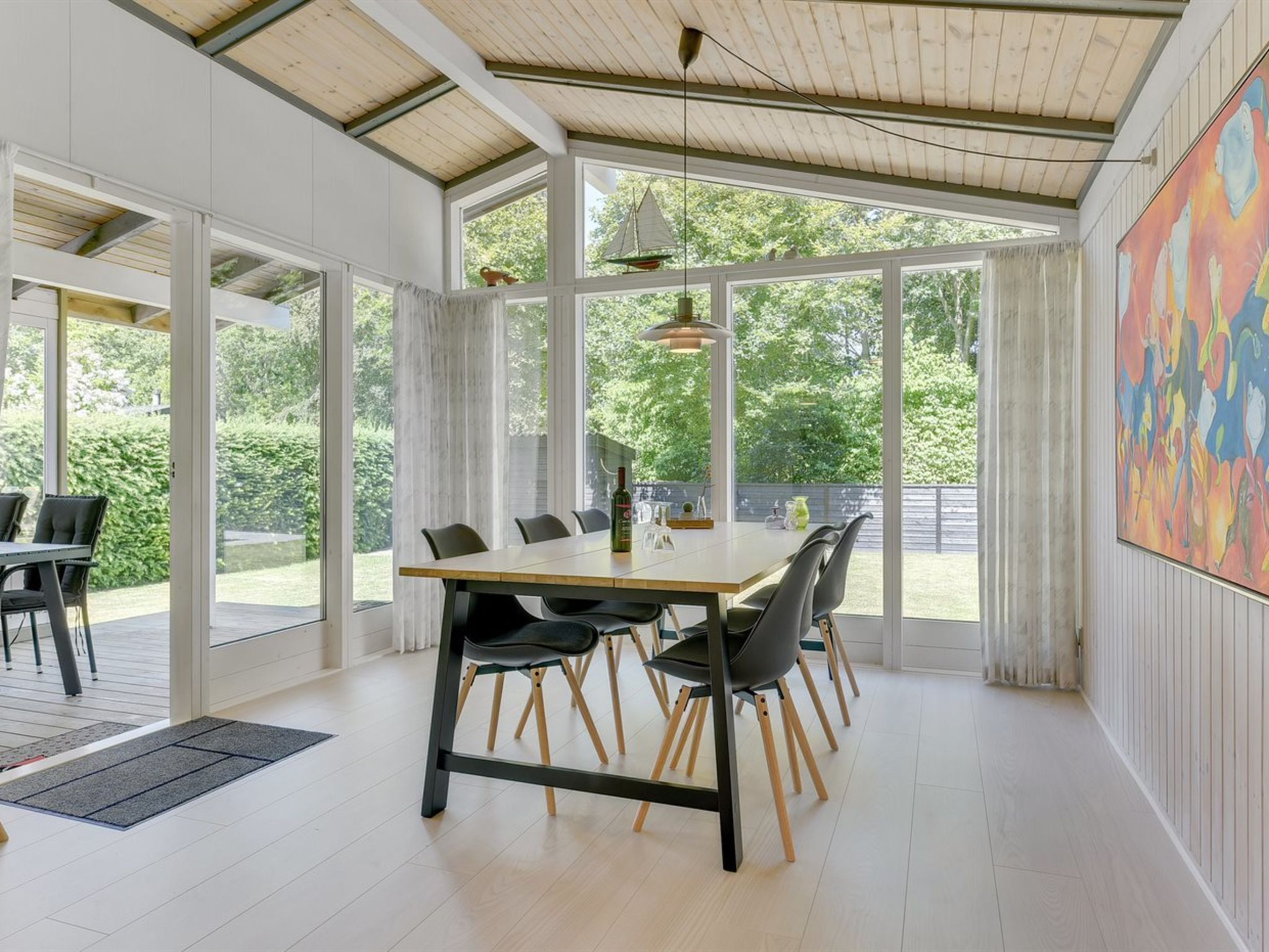 A spacious dining area with a large table and chairs, large windows, and a view of the outdoors.