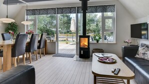 Un salon moderne doté d’un poêle à bois, d’un coin repas et d’un espace détente.