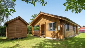 Une cabane en bois avec une véranda et un abri séparé.