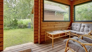 Une cabane en bois avec une terrasse, un canapé et une table.