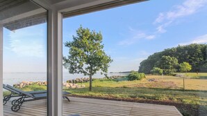 Een terras met uitzicht op een meer, een boom en een gazon.