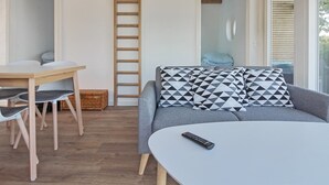 Een moderne woonkamer met een grijze bank, een witte salontafel en een houten ladder tegen de muur.