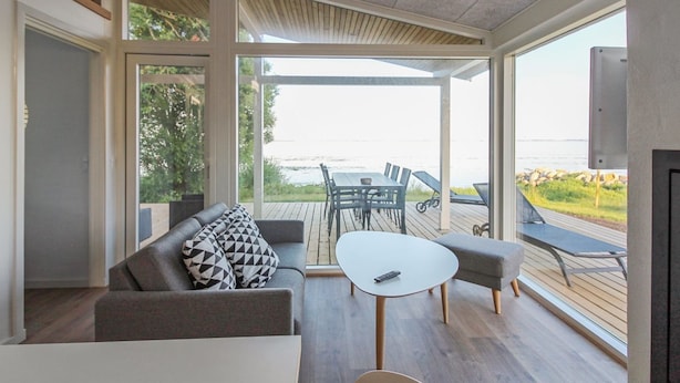 Een moderne woonkamer met een bank, een bijzettafeltje en uitzicht op het groen.