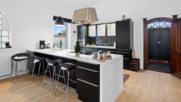 A modern kitchen with a large island, bar stools, and a black and white color scheme.
