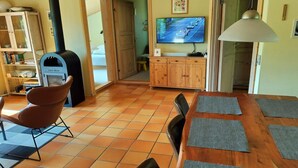 Ein gemütliches Wohnzimmer mit Kamin, Fernseher und Essbereich mit Tisch und Stühlen.
